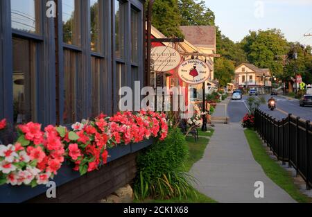 The general view of town of Wilmington and Main Street with flowers on a store window under late afternoon sunlight.Wilmington.Vermont.USA Stock Photo