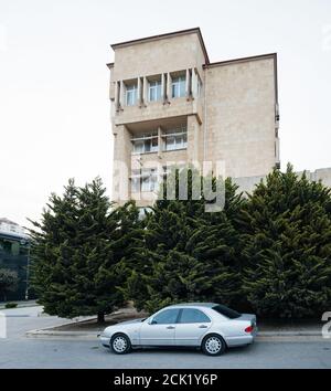 Baku Azerbaijan - May 2 2019: Old Mercedes-Benz E-Klass parked in front of Soviet architecture in central Baku Stock Photo