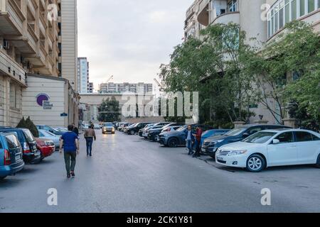 Baku Azerbaijan - May 2 2019: Azeri men in front fo Atlas Medical center and Damir Bank office surrounded by tall apartment building Stock Photo