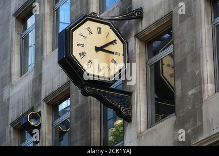 Street clock hang on the wall of a building in London England United Kingdom UK Stock Photo