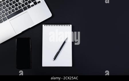 Black office desk with laptop, smartphone, notebook and pen. Top view  Stock Photo
