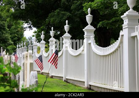 Curved white wooden fence with tombstones and US flags in Old Bennington Cemetery.First Congregational church of Bennington.Bennington.Vermont.USA Stock Photo