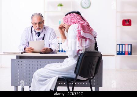 The young male arab visiting experienced male doctor Stock Photo