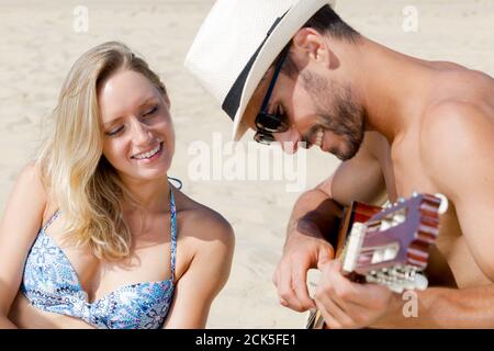 young caucasian couple with guitar on beach Stock Photo