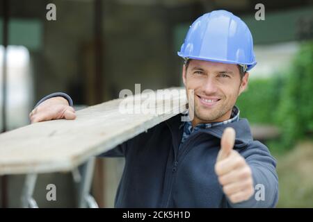 furniture maker carrying wood planks on his shoulder Stock Photo
