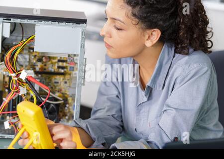 female technician using voltage meter for measuring a pc Stock Photo