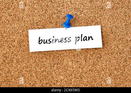Business plan. Text written on a piece of paper or note, cork board background. Stock Photo
