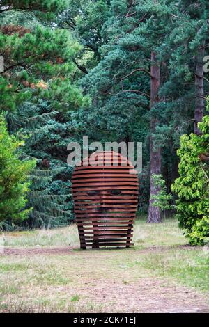 Metal head sculpture in the pinetum at RHS Wisley Gardens, Surrey, England Stock Photo