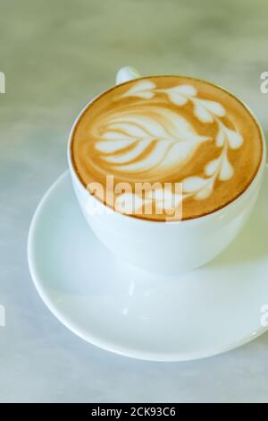 Close-up of a cup of latte is on the marble table, a white ceramic cup of coffee latte with latte art. Flat lay. Top view. Stock Photo