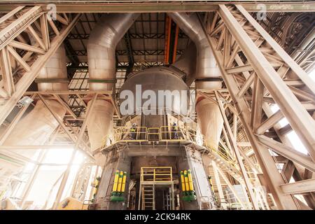 Two male engineers wearing protective equipment check and repair large machine in a factory. Stock Photo