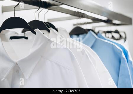 White and blue shirts on hangers in fashion store. Selective focus Stock Photo