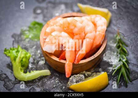 Boiled shrimps prawns on ice frozen at the seafood restaurant fresh shrimp on dark plate with lemon rosemary ingredients herb and spices for cooking s Stock Photo