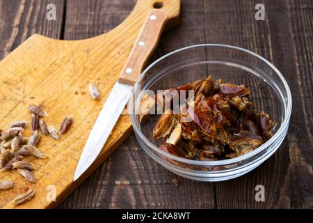 Hushaf - date milk, traditional Ramadan dish, cooking, ingredients, pitted dates in a plate, knife and seeds on a cutting board on the wooden table Stock Photo