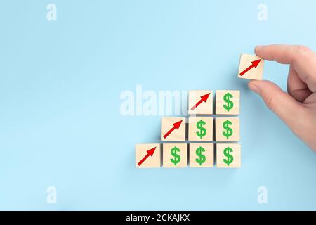 concept of revenue growth. growth on stacked wooden cubes on blue background. Financial or business growth concept. arrows and dollar icons on wooden Stock Photo