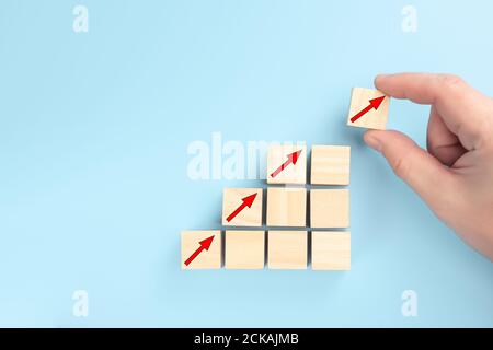concept of revenue growth. growth on stacked wooden cubes on blue background. Financial or business growth concept. arrows icons on wooden cubes. Hand Stock Photo