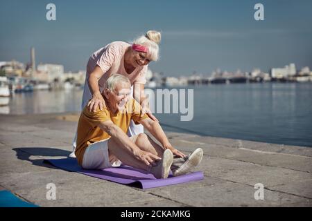 Pensioner doing a stretching exercise on the mat Stock Photo