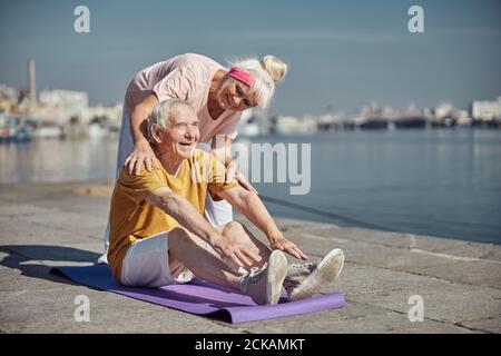 Joyful elderly man doing a stretching exercise Stock Photo