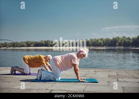 Attractive senior lady and her spouse doing a stretching exercise Stock Photo