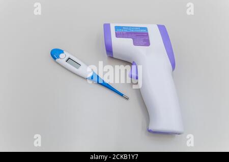 Non-contact infrared thermometer and electronic thermometer on a grey background.Vaccination against the virus. Stock Photo