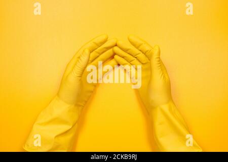 hands in yellow gloves on a yellow background. Stock Photo