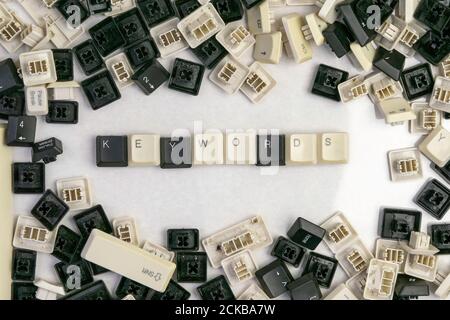 keying works on microstocks, the word keywords folded from the keys of the old keyboard, surrounded by randomly scattered keys Stock Photo