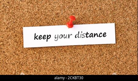 Keep your distance. Text written on a piece of paper or note, cork board background. Stock Photo