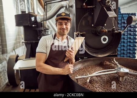 Handsome young man standing by coffee roasting machine Stock Photo