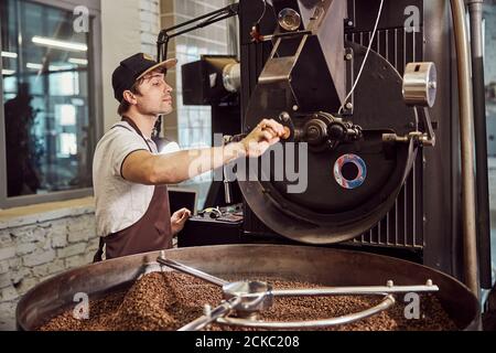 Handsome young man using industrial coffee roasting machine Stock Photo