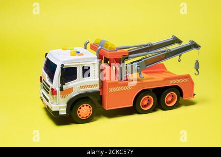 Toy orange tow truck on yellow background banner with space for text. Children's car for loading and transporting cars Stock Photo