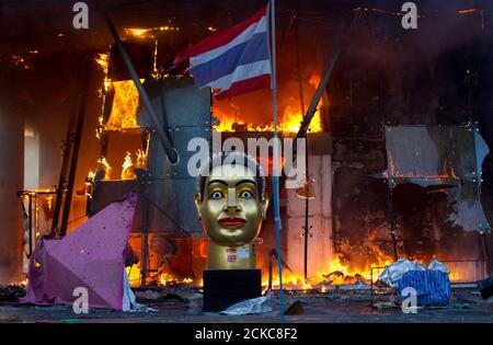 A statue and a torn Thai national flag remain in front of Bangkok's Central World shopping mall, which was gutted by fire after army soldiers advanced towards an encampment of thousands of anti-government 'red shirt' protesters, May 19, 2010. Rioting and fires swept Bangkok on Wednesday after troops stormed a protest encampment, forcing protest leaders to surrender but sparking clashes that killed at least four people and triggered unrest in northern Thailand.    REUTERS/Adrees Latif  (THAILAND - Tags: CIVIL UNREST POLITICS IMAGES OF THE DAY)