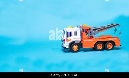 Toy orange tow truck on blue background banner with space for text. Children's car for loading and transporting cars Stock Photo