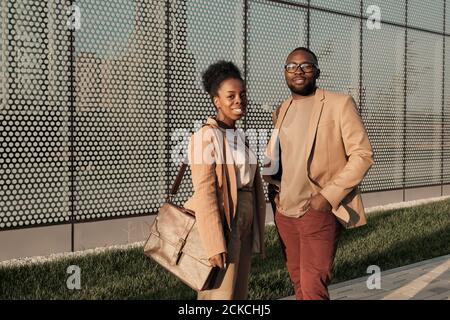 Portrait of African young couple in elegant suits smiling at camera while standing in the city Stock Photo