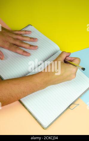 Vertical shot of male writing in a notebook - education concept Stock Photo