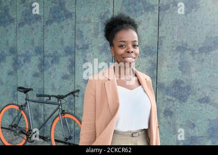 Portrait of African young woman smiling at camera in the city with her bike in the background Stock Photo