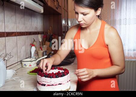 Young woman decorates a cake in the kitchen Stock Photo