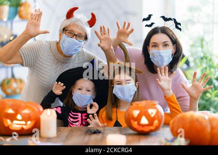 Happy family celebrating Halloween. Grandmother, mother and children wearing face masks protecting from COVID-19. Stock Photo