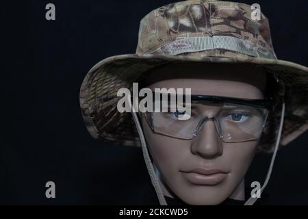Mannequin face in a military cap and protective glasses isolated on a black background Stock Photo