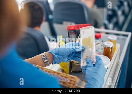 Back view focused image of table with snack and drinks while female air hostess serving meal for the passenger of first class Stock Photo