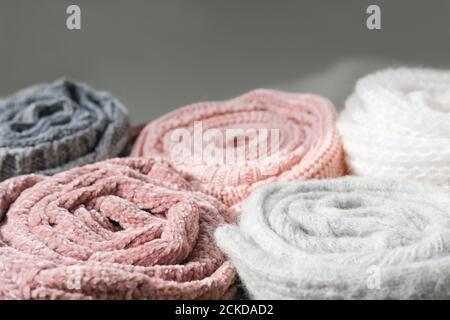 rolled knitted sweaters in grey and pink tones. autumn and winter warm pullovers. textured background. cozy clothes for cold season. Stock Photo