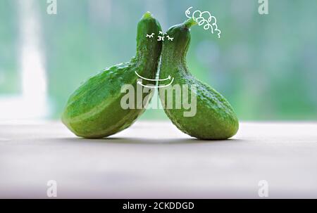 funny kissing cucumbers. cartoon characters in love. paint art on a vegetables. love and togetherness concept. cuddling cuccumbers. selective focus.  Stock Photo