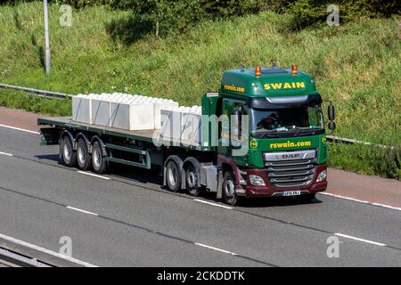 Swain Haulage delivery trucks, low-loader lorry, transportation, truck, cargo carrier, DAF vehicle, European commercial transport industry HGV, M6 at Manchester, UK Stock Photo