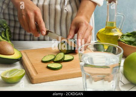 Woman cutted cucumber on white wooden table Stock Photo
