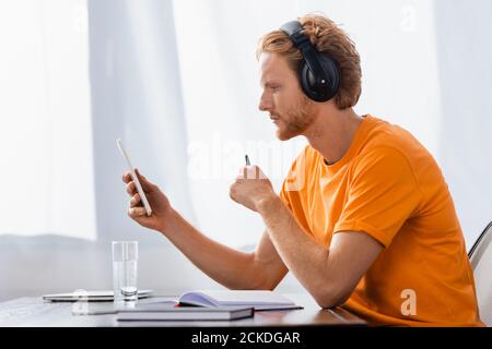 side view of pensive student in wireless headphones using digital tablet at home Stock Photo