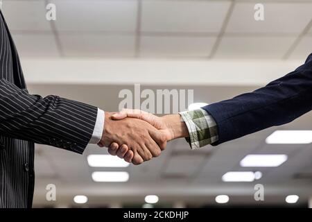 Close up pic of two young Asian men shaking hands, greeting with client, firm handshake, agreement. Stock Photo