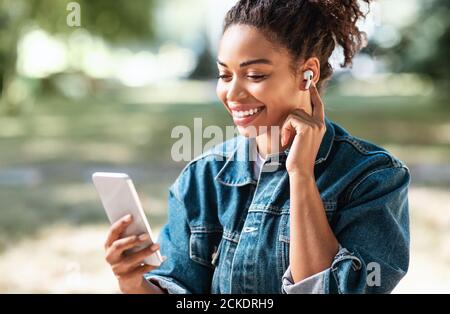 Black Millennial Girl Using Phone Making Video Call Siitting Outside Stock Photo