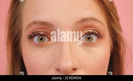 makro shot of scared surprised green woman eyes isolated on pink background. High quality photo Stock Photo