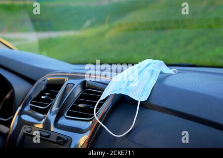 Medical mask on console in auto for corona virus protection. Coronavirus pandemic prevention. Stock Photo