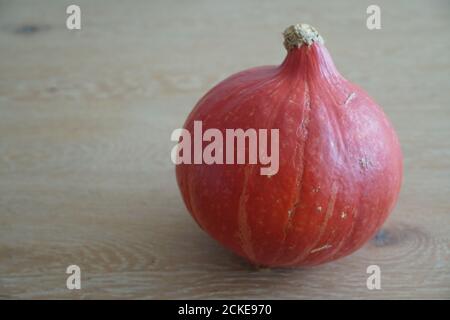 Pumpkin Hokkaido a whole ripe fruit on the wooden background with a lot of copy space on the wooden table. Seasonal vegetable ideal as a background. Stock Photo