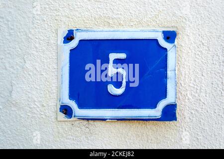 Street door number five on cement wall, address plate Stock Photo