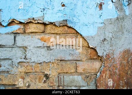 Brick old weathered wall with cracked painted plaster as a background Stock Photo
